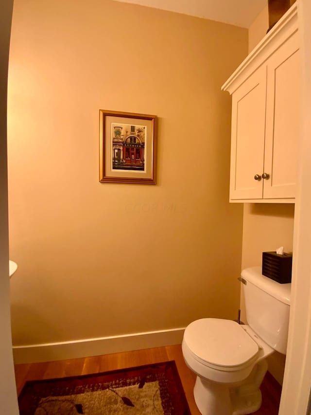 bathroom featuring baseboards, toilet, and wood finished floors