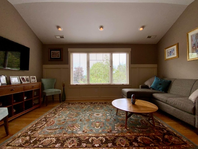 living area with light wood-style flooring, visible vents, and vaulted ceiling