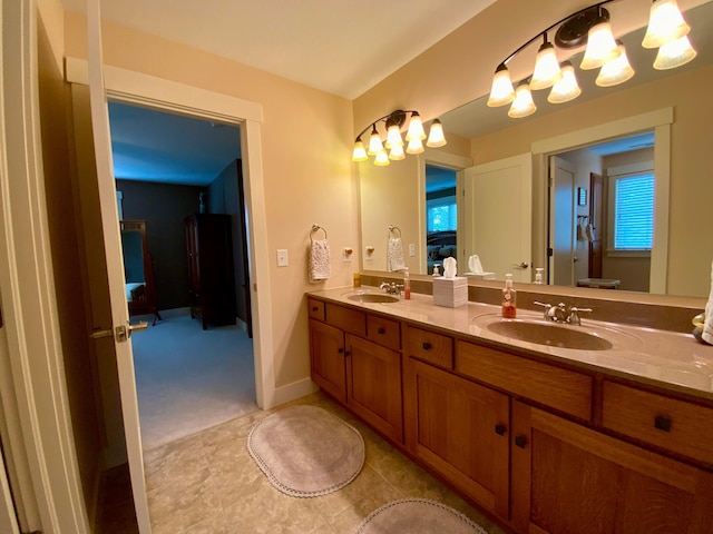 ensuite bathroom featuring baseboards, double vanity, a sink, and connected bathroom