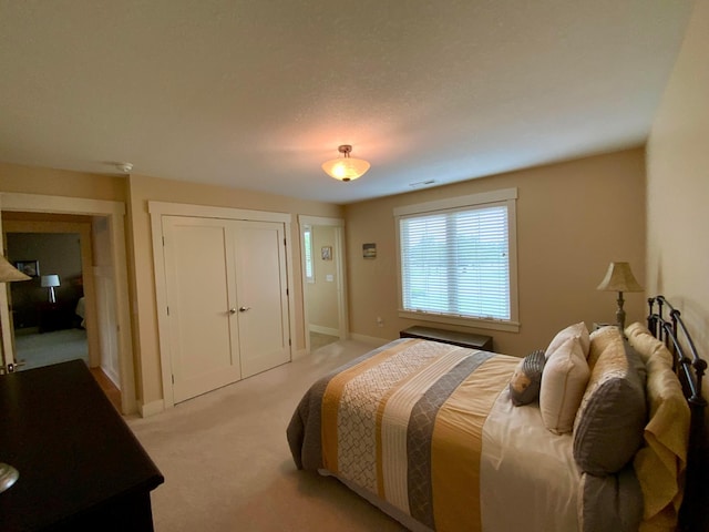 bedroom featuring a closet, light colored carpet, visible vents, and baseboards