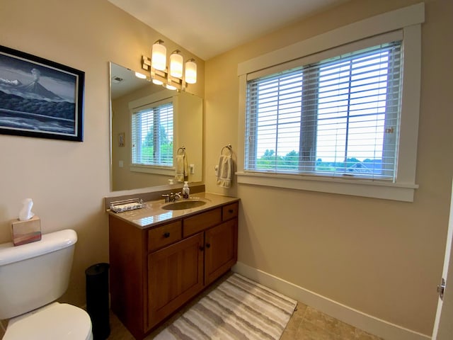 bathroom featuring toilet, vanity, and baseboards