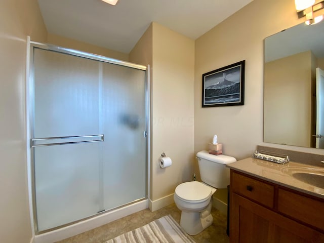 full bath featuring toilet, a stall shower, vanity, and baseboards