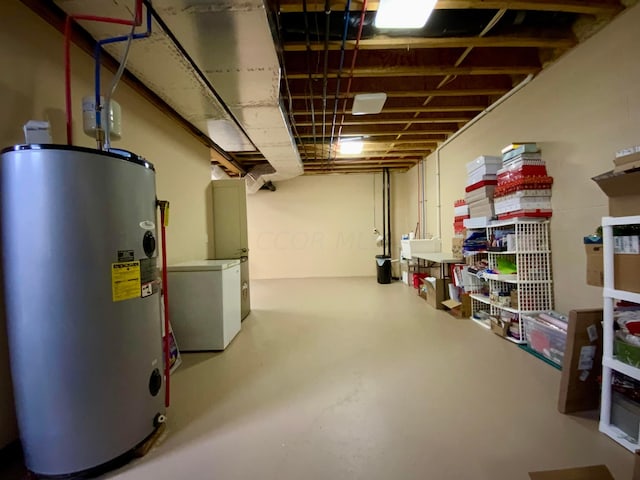 unfinished below grade area featuring refrigerator and water heater