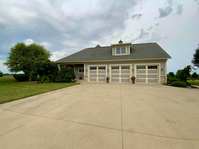 view of front of property featuring driveway, stone siding, an attached garage, and a front lawn