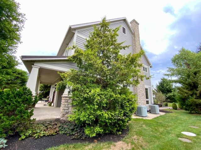 view of side of home with a yard and central air condition unit