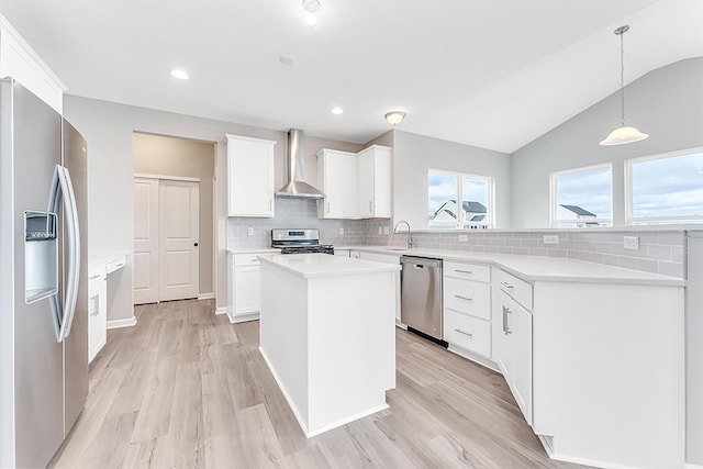 kitchen featuring white cabinets, wall chimney exhaust hood, lofted ceiling, and appliances with stainless steel finishes