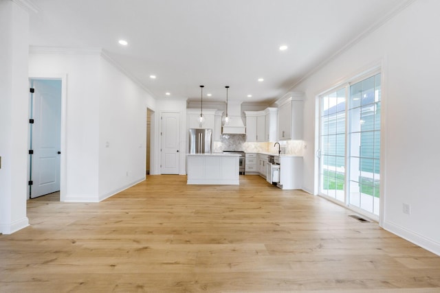 kitchen with decorative backsplash, appliances with stainless steel finishes, a center island, white cabinetry, and hanging light fixtures