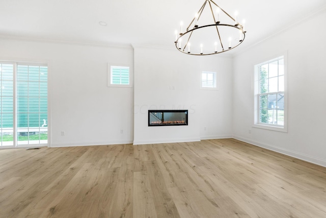 unfurnished living room with light wood-type flooring, crown molding, and an inviting chandelier