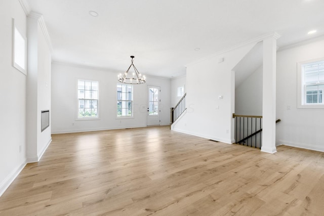 unfurnished living room with a chandelier, light hardwood / wood-style flooring, and crown molding