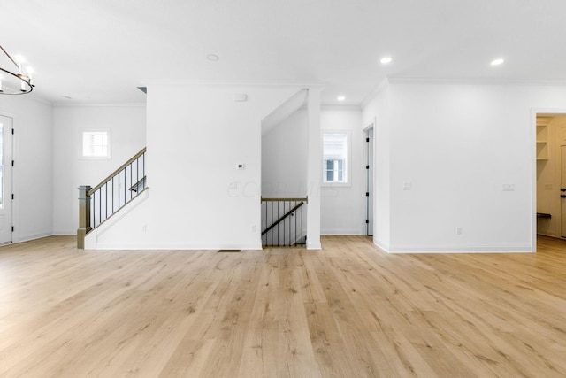 unfurnished living room with a wealth of natural light, light wood-type flooring, and ornamental molding