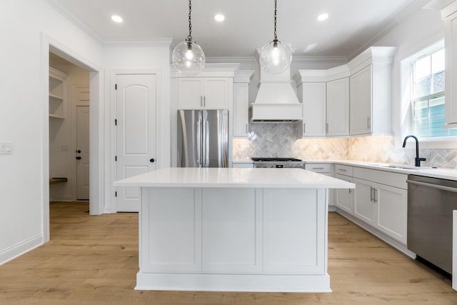 kitchen featuring sink, a center island, pendant lighting, custom range hood, and appliances with stainless steel finishes