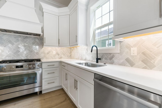 kitchen with white cabinets, sink, custom range hood, and stainless steel appliances