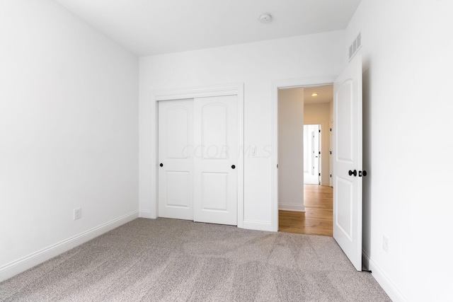 unfurnished bedroom featuring light carpet and a closet