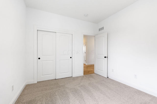 unfurnished bedroom with a closet and light colored carpet