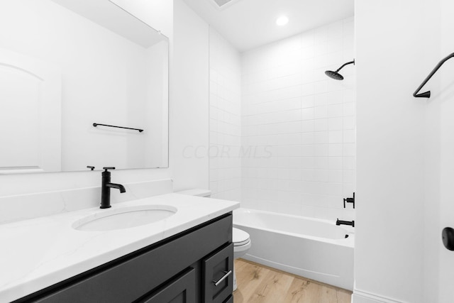 full bathroom featuring vanity, hardwood / wood-style flooring, toilet, and tiled shower / bath