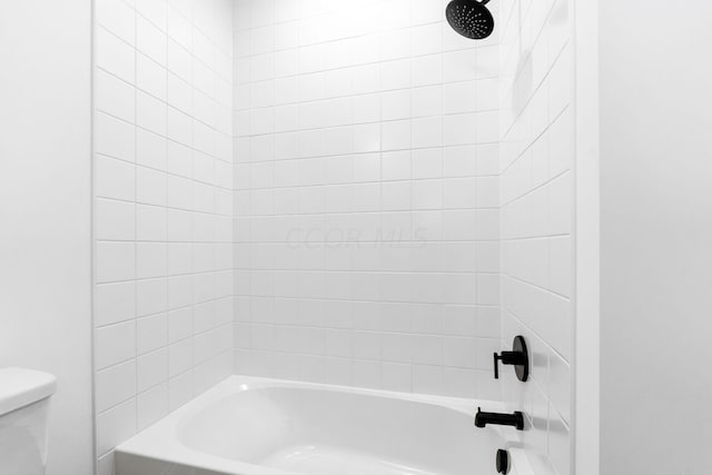 bathroom featuring toilet and tiled shower / bath