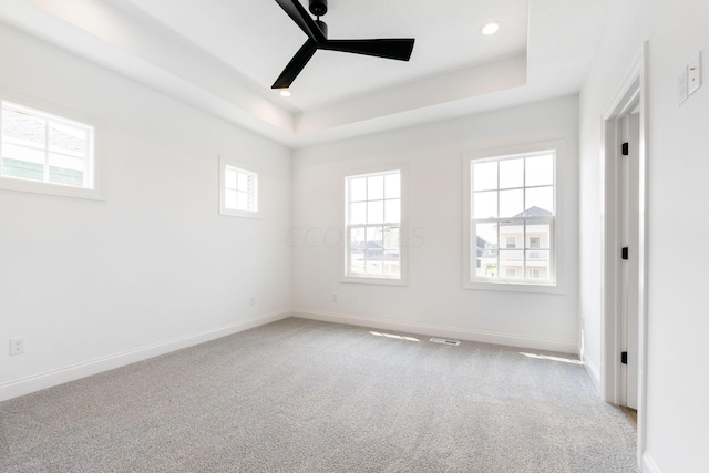 unfurnished room featuring a tray ceiling, ceiling fan, and light carpet