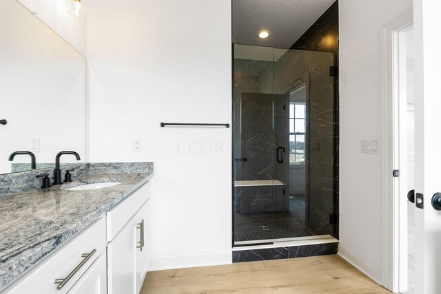 bathroom featuring hardwood / wood-style floors, vanity, and a shower with door