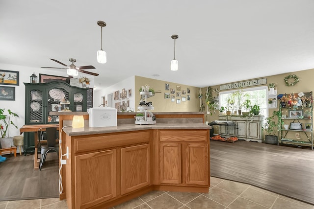 kitchen featuring ceiling fan, a center island, light wood-type flooring, and hanging light fixtures