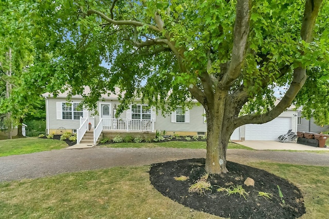 view of front of property featuring covered porch, a garage, and a front lawn