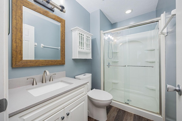 bathroom with hardwood / wood-style floors, a textured ceiling, toilet, and walk in shower