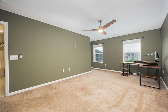 carpeted home office featuring ceiling fan