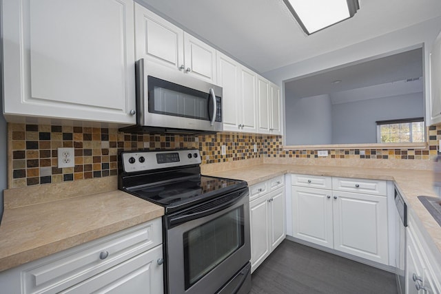 kitchen with appliances with stainless steel finishes, backsplash, white cabinetry, and dark wood-type flooring