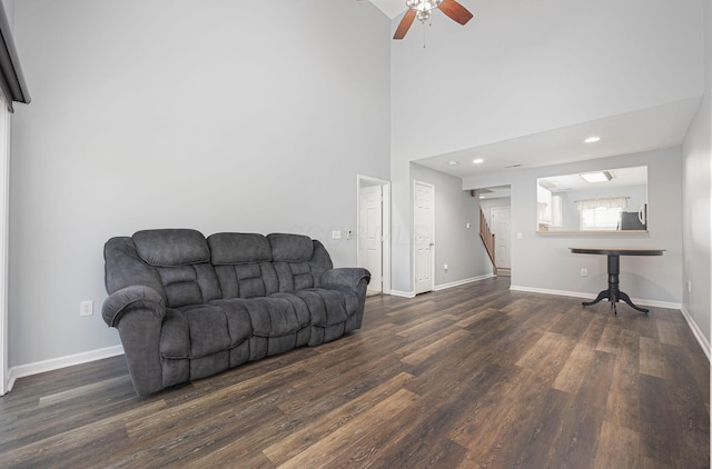 living room featuring ceiling fan, dark hardwood / wood-style flooring, and a high ceiling