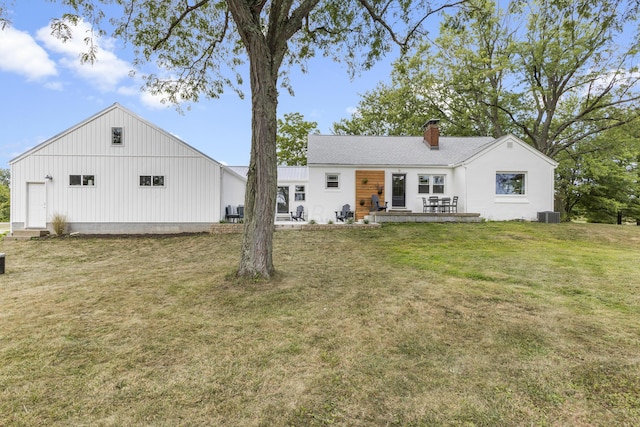 back of house with central air condition unit and a yard