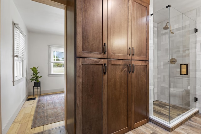 bathroom with hardwood / wood-style flooring, toilet, and an enclosed shower