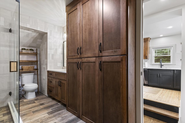 bathroom with hardwood / wood-style floors, vanity, toilet, and tile walls