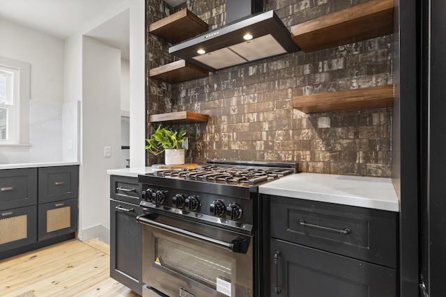 kitchen with backsplash, extractor fan, high end stainless steel range oven, and light wood-type flooring