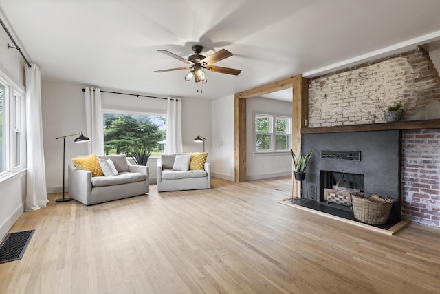 living room with a fireplace, light hardwood / wood-style floors, plenty of natural light, and ceiling fan