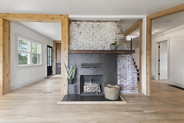 unfurnished living room featuring light wood-type flooring and a brick fireplace