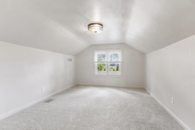 additional living space with light carpet and vaulted ceiling