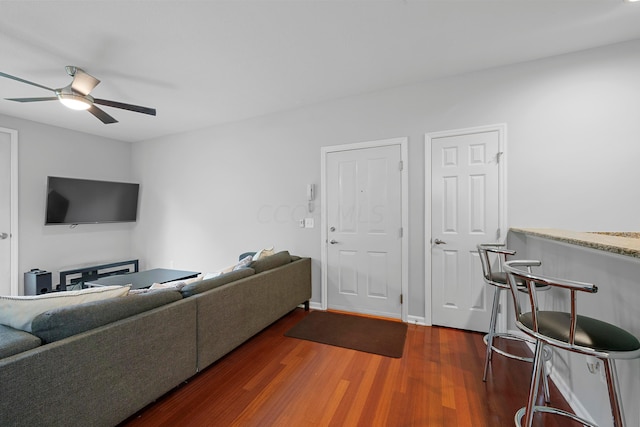 living room featuring ceiling fan and dark wood-type flooring