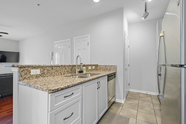 kitchen with light stone countertops, appliances with stainless steel finishes, ceiling fan, sink, and white cabinets