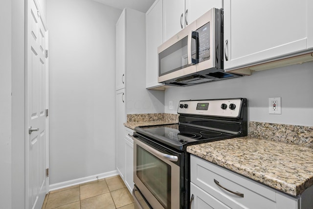 kitchen featuring white cabinets, appliances with stainless steel finishes, light tile patterned floors, and light stone countertops