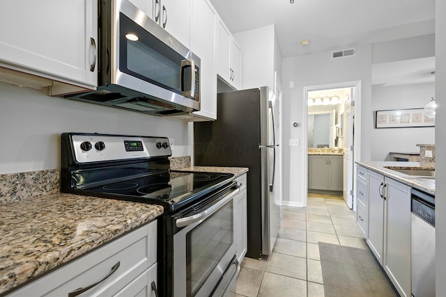 kitchen with white cabinetry, stainless steel appliances, and light stone counters