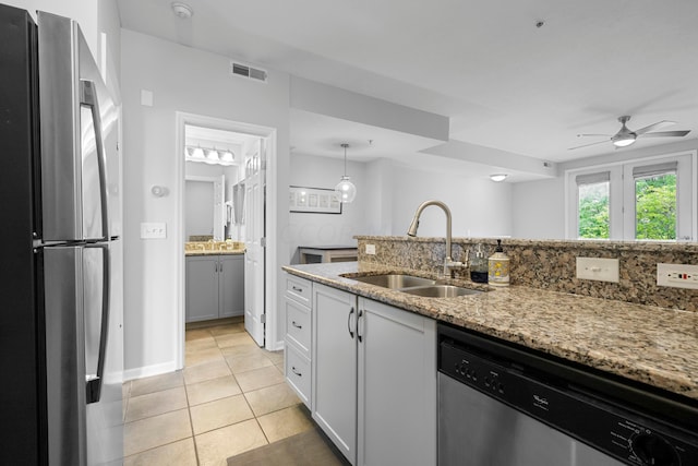 kitchen with sink, ceiling fan, light tile patterned flooring, light stone counters, and stainless steel appliances