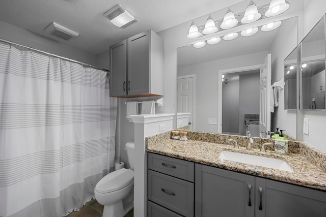 bathroom featuring vanity, a textured ceiling, and toilet