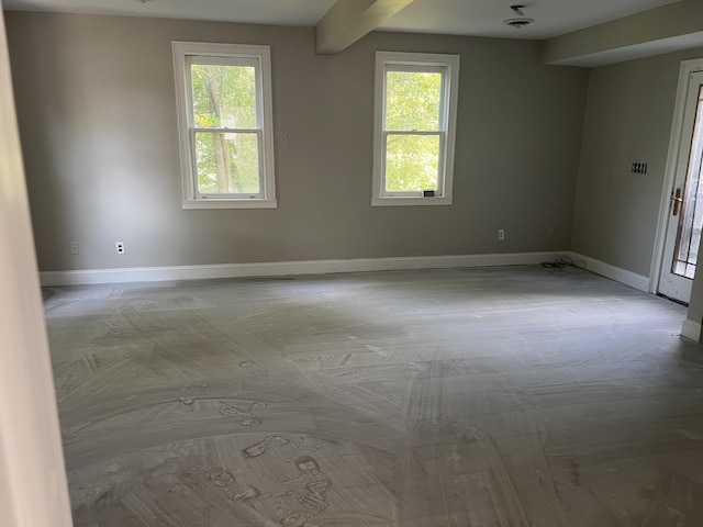 empty room featuring a wealth of natural light and beamed ceiling