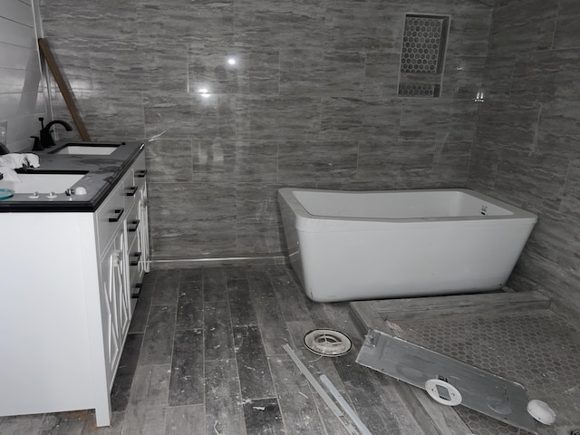 bathroom with a tub, vanity, tile walls, and hardwood / wood-style flooring