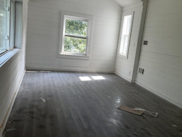 unfurnished room with dark hardwood / wood-style flooring, lofted ceiling, and wooden walls