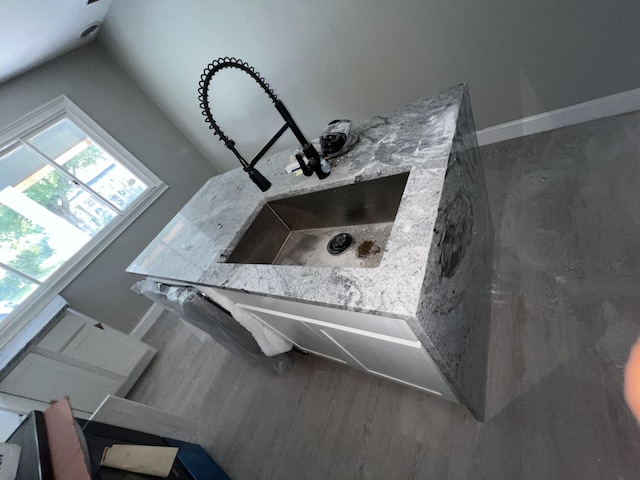 room details with light stone countertops, hardwood / wood-style flooring, and sink