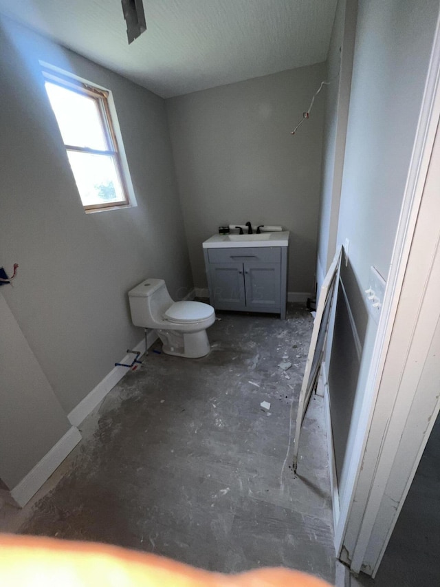 bathroom with vanity, toilet, and concrete flooring