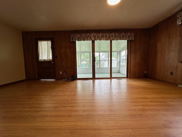 empty room with light wood-type flooring and wooden walls