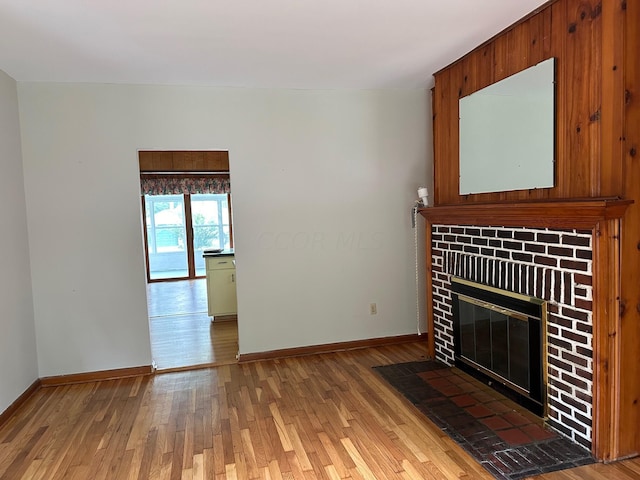 unfurnished living room with hardwood / wood-style flooring and a brick fireplace