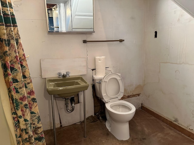 bathroom with toilet, sink, and concrete floors