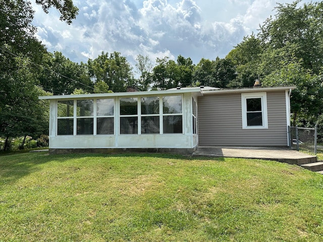 rear view of house with a sunroom, a yard, and a patio